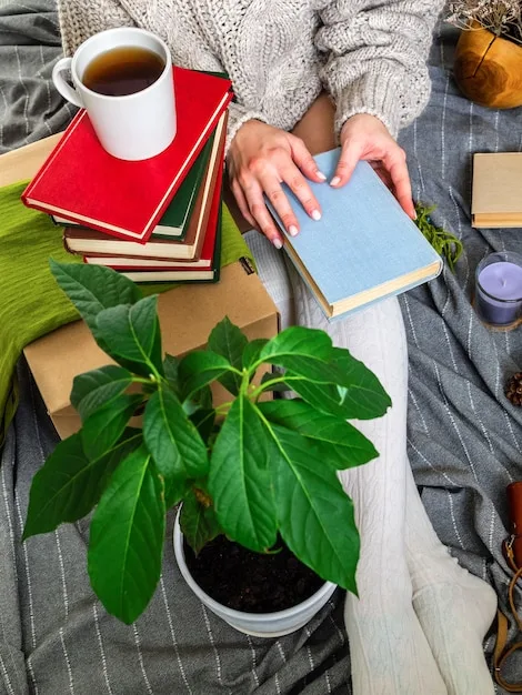 A person sitting comfortably in an armchair, holding a journal and a pen, with a cup of tea on a nearby table. The room is warmly lit and decorated with plants, creating a serene atmosphere.