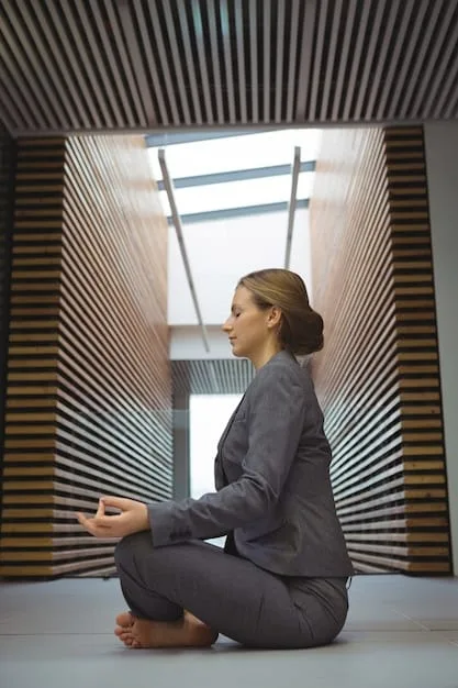 A person sitting cross-legged in a modern office space, meditating. The background shows blurred office activities, emphasizing the contrast between the calm individual and the busy environment. Soft, diffused lighting adds to the serene atmosphere.