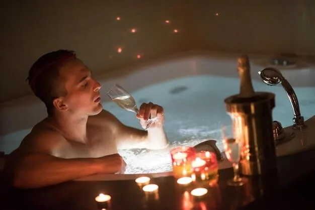 A person relaxing in a bubble bath with candles lit around the tub, showcasing a serene and calming self-care experience.