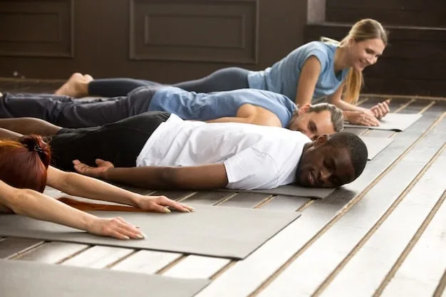 A person is lying in Savasana (corpse pose) during a gentle yoga session. They are on a yoga mat in a softly lit room, eyes closed, with a blanket draped over them for added comfort. Their expression is peaceful and serene. The scene conveys relaxation and deep rest.