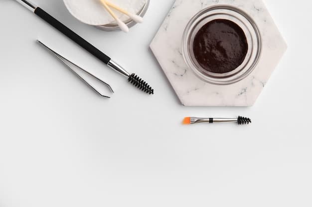 A kit of essential brow shaping tools laid out on a makeup table, featuring tweezers, brow scissors, a spoolie brush, an angled brush, and various brow pencils and powders.