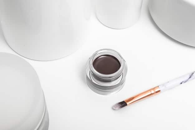 Assortment of minimal makeup products like tinted moisturizer, concealer, brow gel, and lip balm, arranged on a clean white surface.