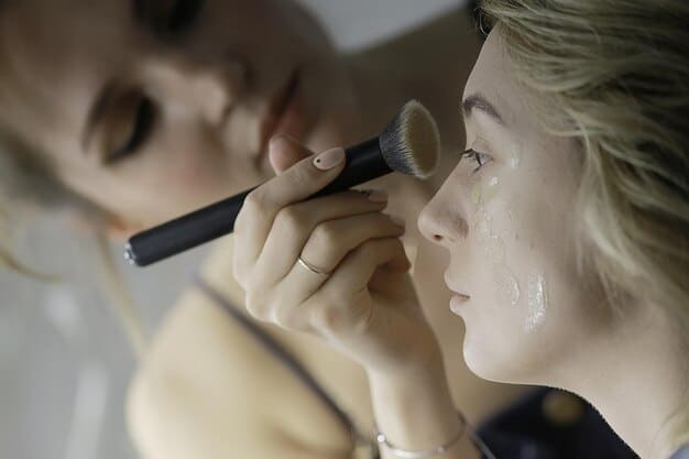 A makeup artist applying liquid highlighter to a model's cheekbone, demonstrating precise application with a focus on the light reflecting off the skin.