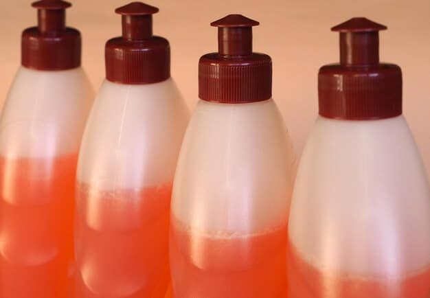 Close-up of a variety of gentle cleansers displayed on a shelf in a well-lit beauty store. The cleansers are in different bottles, some foam, some cream, but all are labeled as 