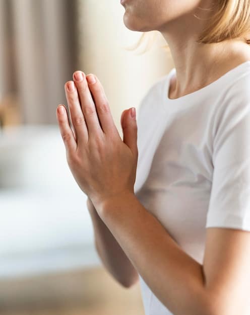 A close-up shot of hands in a prayer position during meditation. The background is blurred, emphasizing the hands and the feeling of peace and focus. Soft, natural lighting highlights the texture of the skin.