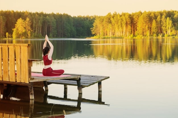 A serene outdoor setting with a person practicing yoga on a wooden deck, overlooking a lake surrounded by trees. The sky is clear and blue, and the atmosphere promotes peace and tranquility.