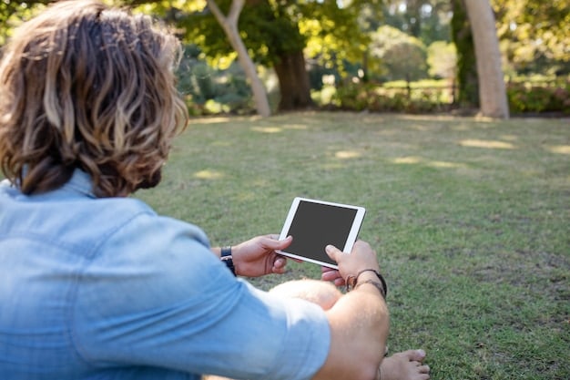 A person placing their smartphone on a charging stand, symbolizing a digital detox, with a blurred background of a family playing in the garden.