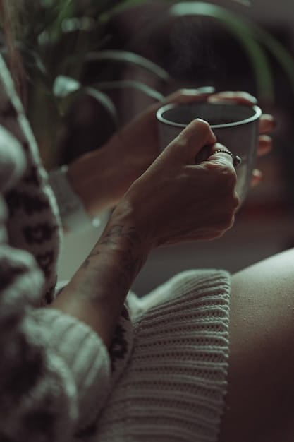 A close-up of a person's hands gently holding a cup of herbal tea while sitting by a window with soft sunlight coming in. The scene is calm and peaceful, representing relaxation and self-care.