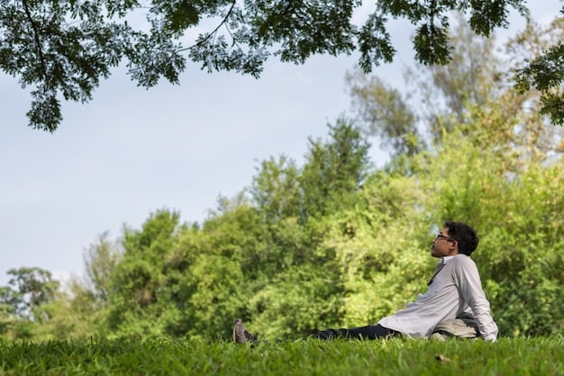 A person meditating outdoors in a quiet park, with eyes closed and a peaceful expression. The background shows green trees and soft sunlight, creating a serene atmosphere.