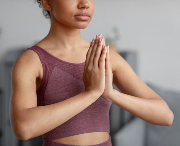 A close-up shot of hands gently folded in a prayer position during a gentle yoga session. The hands are resting on the knees while the person is in a comfortable seated position. The background is softly blurred, depicting a calm and serene environment.