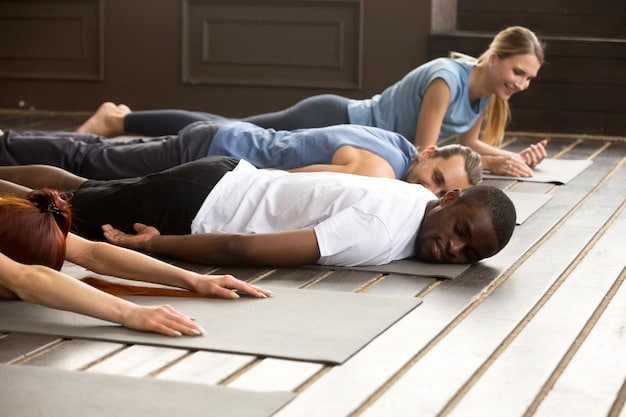 A person is lying in Savasana (corpse pose) during a gentle yoga session. They are on a yoga mat in a softly lit room, eyes closed, with a blanket draped over them for added comfort. Their expression is peaceful and serene. The scene conveys relaxation and deep rest.