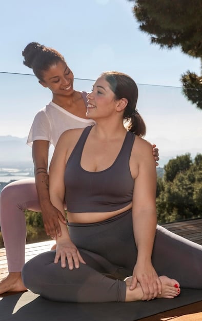 A personal trainer demonstrating a modified yoga pose to a plus-size client in a private studio setting.