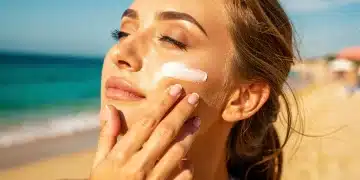 Woman applying sunscreen to face on beach for summer sun protection